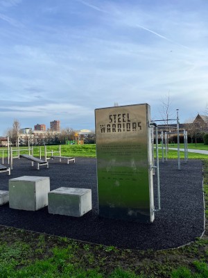 Signage for the outdoor gym. You must cross about 2 metres of grass to get between the tarmac path and the rubber safety flooring of the gym area.