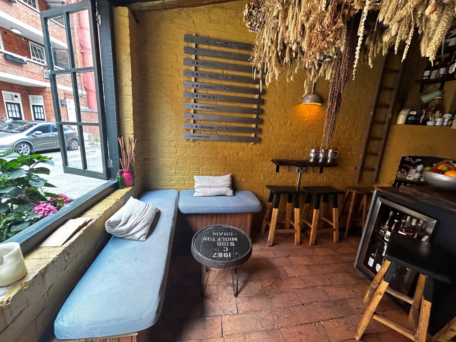 From entrance facing left. Cushioned bench along left and back wall with low table. High table and stools ahead to right. Bar and stools to right.