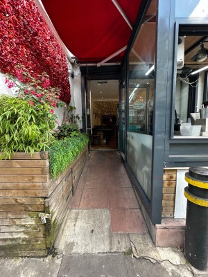 From pavement looking straight at built-in ramp ahead leading up to entrance. Outdoor counter to right.