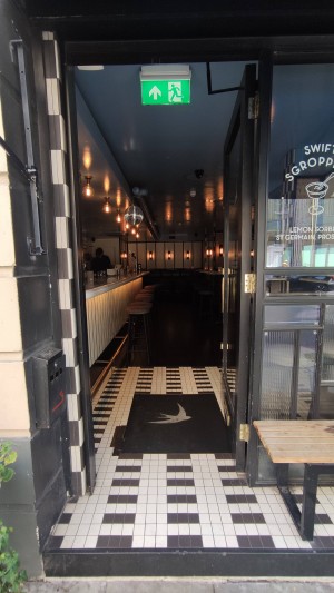 Glass door with black frames ahead. Push on right to open. No handle.