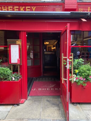 First out of three sets of doors ahead. Glass door with red frame. Pull open via vertical golden handrail on left.
