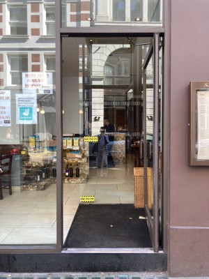 Glass entrance door. Push open via handle on left. Dividing glass wall ahead. Entrance to the left.