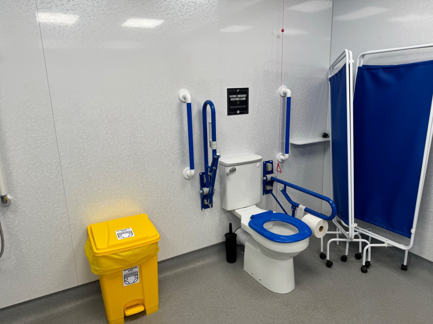 Foot pedal nappy bin to the left of the toilet