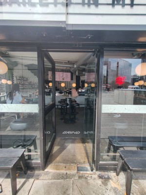 Single glass door in black metal frame. Push on left of door to open.