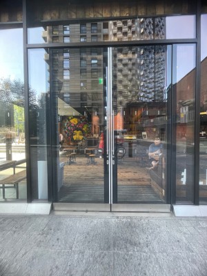 Glass doors with black frame. Silver vertical handles in centre. Pull to open.