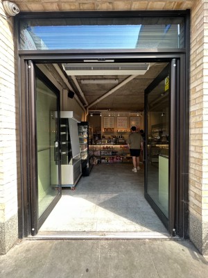 Glass doors with black frames. Black vertical handles in centre, push to open.
