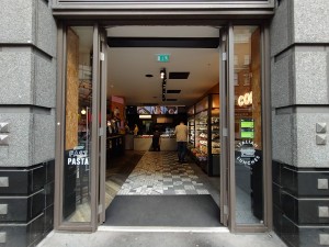 Glass door with brown frame, silver vertical handle in the middle. Push to open.