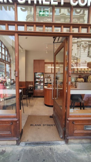 Glass door with wooden frames ahead. Push via metal handle on left to open.