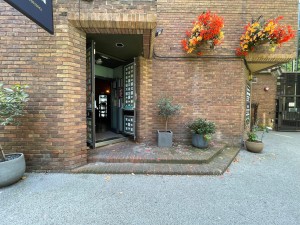 From pavement, facing straight. Path ahead to two steps up. First set of doors to main area on left after steps.