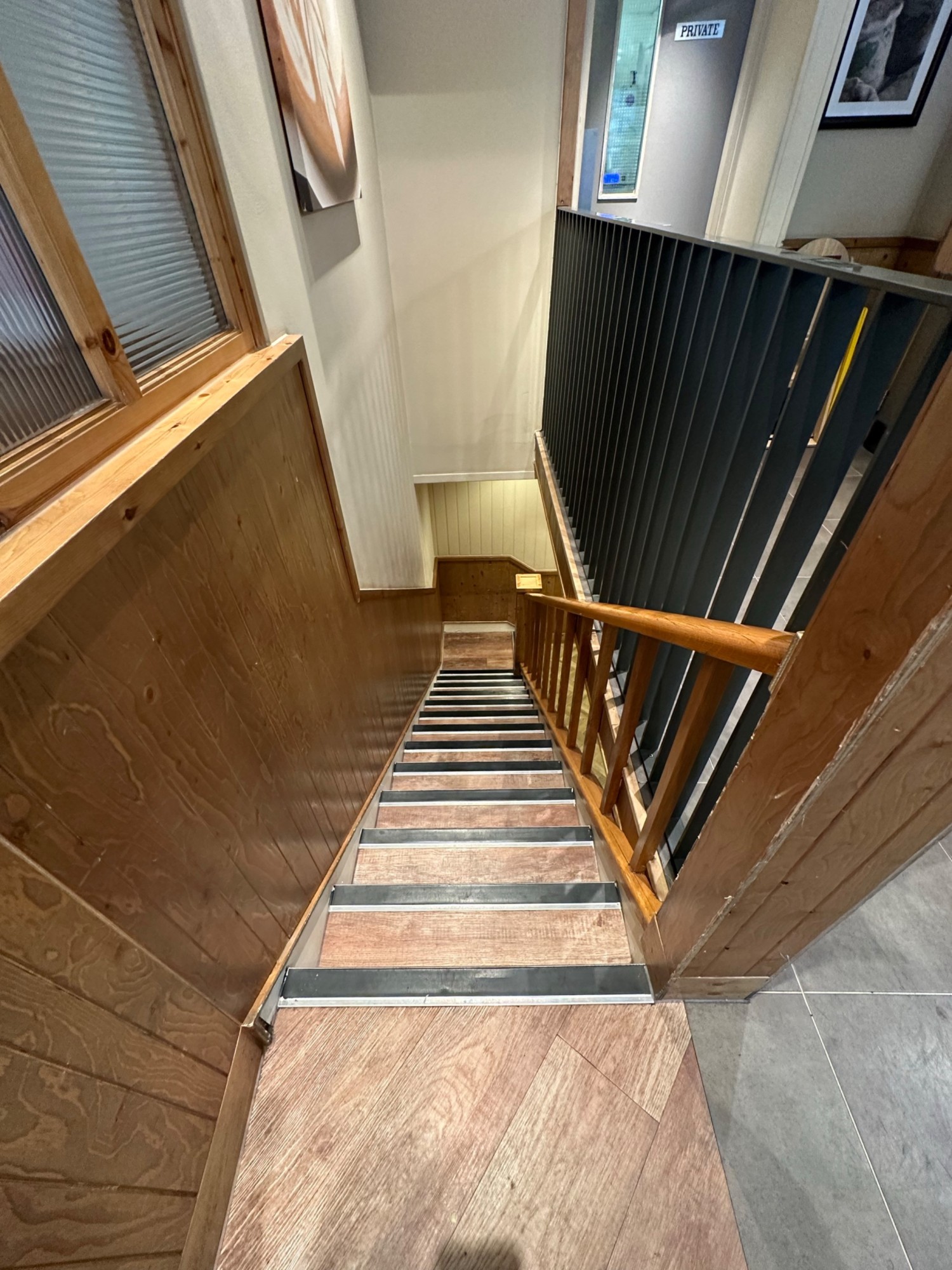 From divider, facing right. First flight of stairs ahead. Wooden handrail along right.