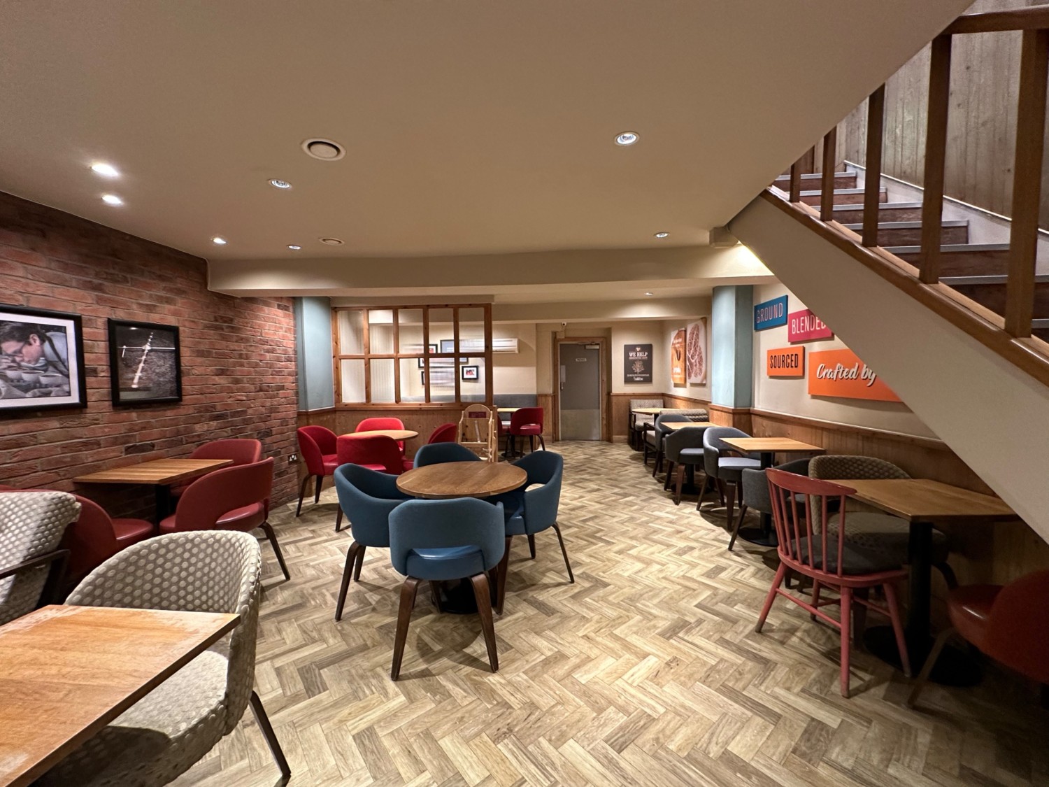 From bottom of stairs, facing right. Path ahead. Tables and chairs along left and right. Wood and glass divider ahead to left.