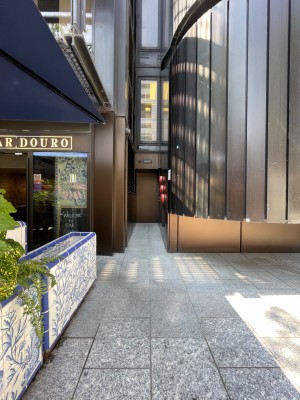 From pavement. Path to entrance ahead. Tiled wall along left.