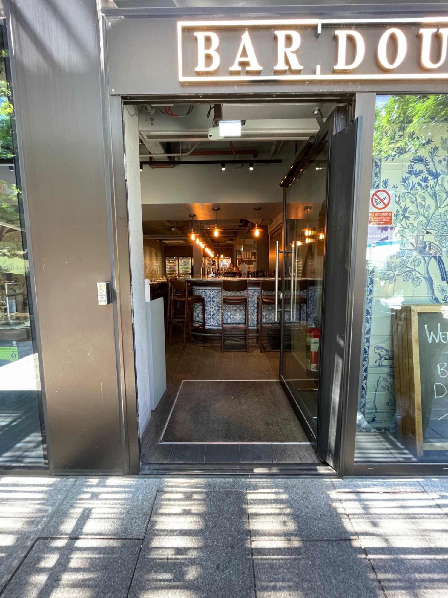 From end of path, facing right. Metal framed door ahead. Push button on left to open.