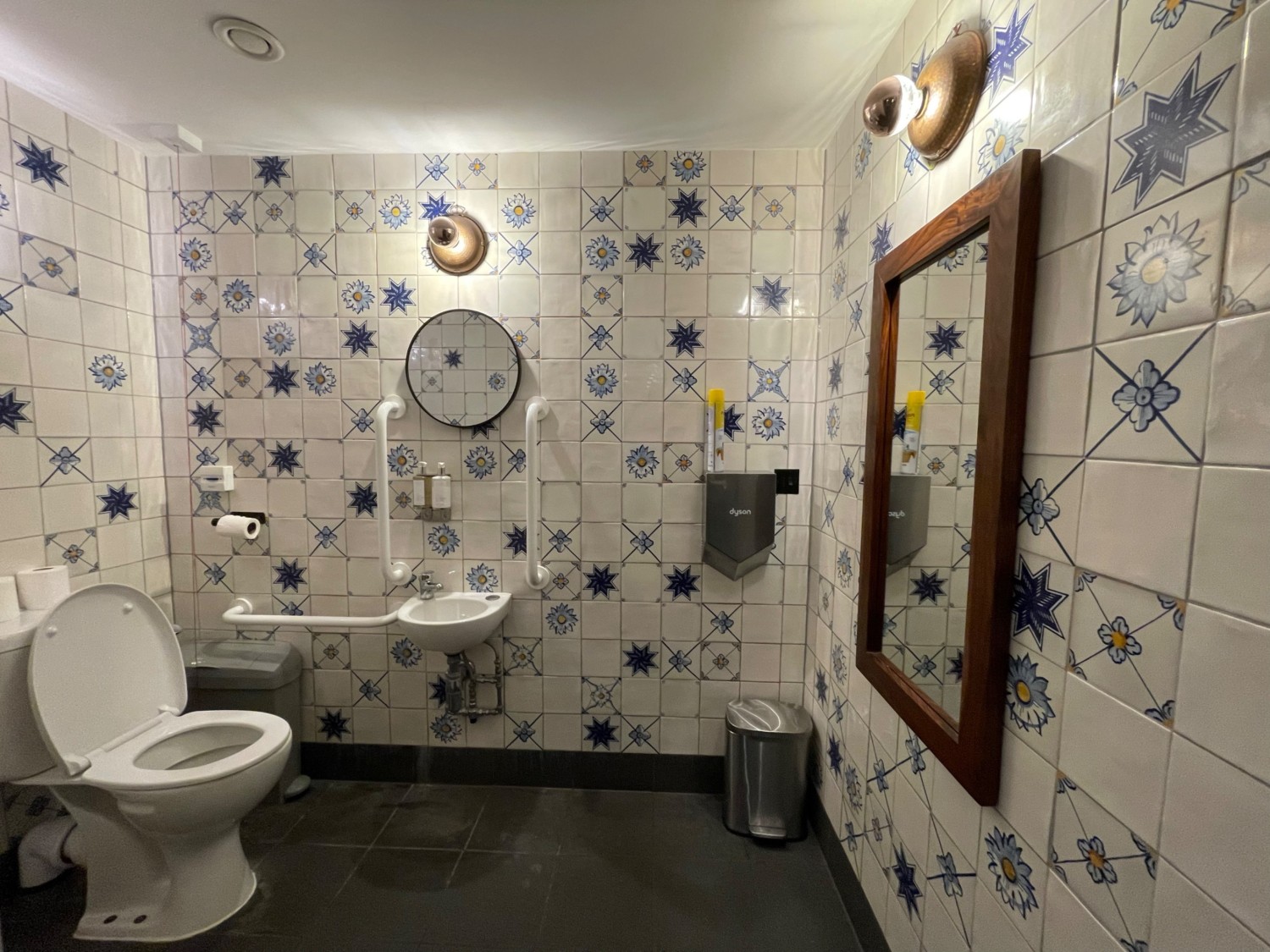 From doorway, facing straight. Toilet at back left. Emergency cord on its right. Sink on back wall.