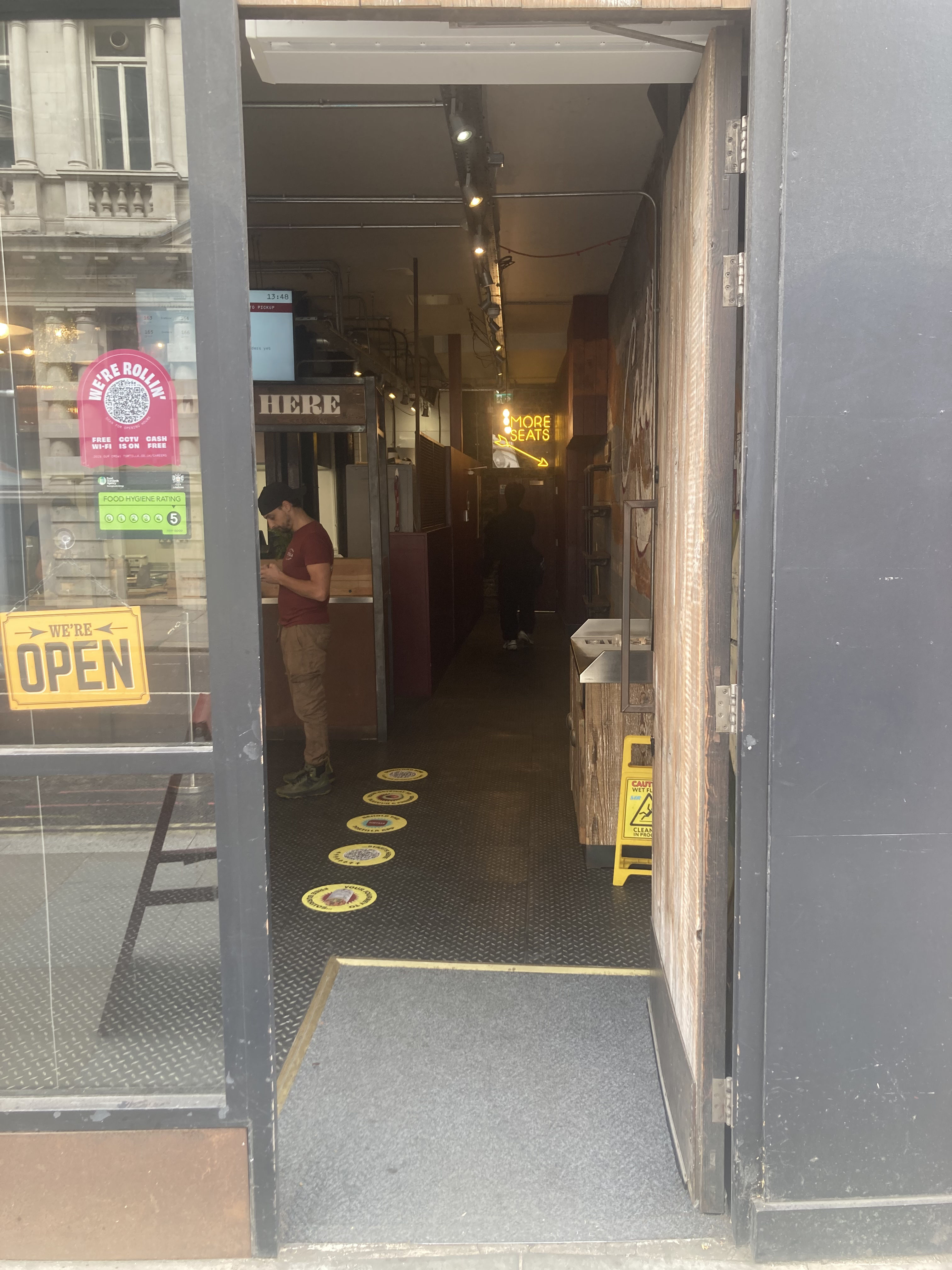 Wooden entrance door. Push open via vertical handrail on left.