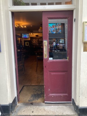 Double glass door with red wooden frame. Push open via metal pads on center.
