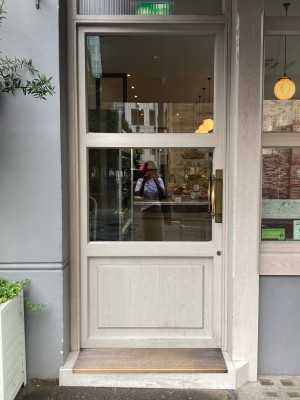 Glass door with white wooden frame. Push open via handle on right.