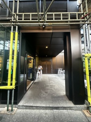 From side walk, facing venue. Black archway ahead.