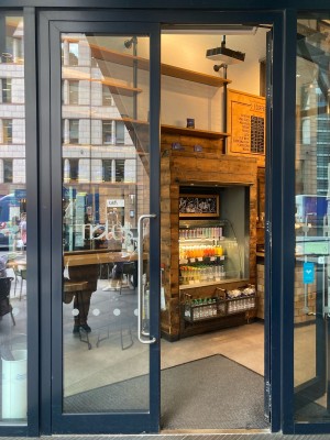 Double glass door with black frame. Pull open via vertical handrail in center.