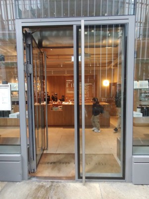 Double glass doors in silver metal frame. Push silver, metal, vertical handles from centre to open.