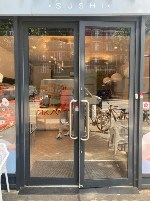 Double glass door with black frame. Pull open via handles in center.