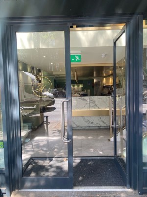 Double glass door with black frame. Push open via handles in center.