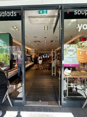 Glass door with silver vertical handle on left. Push to open.