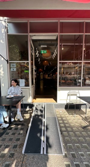 Ramp available upon request leading up to entrance. Tables and chairs to left and right of entrance.