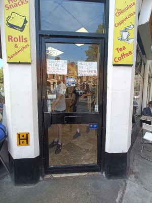 Glass door with black frame. Handle on left. Push to open.