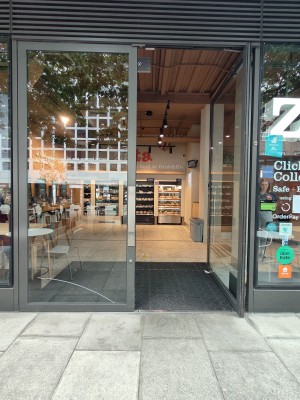 Facing grey framed double glass doors. Push silver metal panels in centre of door to open.