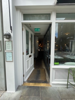 Single white wooden door with glass pa els. Push vertical golden handle on right to open.
