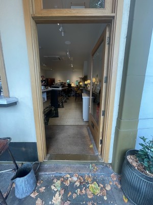 From pavement, facing straight. Glass door with light brown frame. Push to open.