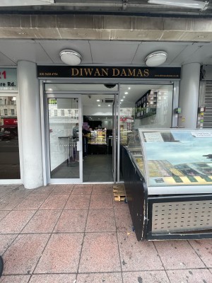 From pavement, facing straight. Glass doors with grey frame ahead. Metal handles push to open from centre. Glass display to right.