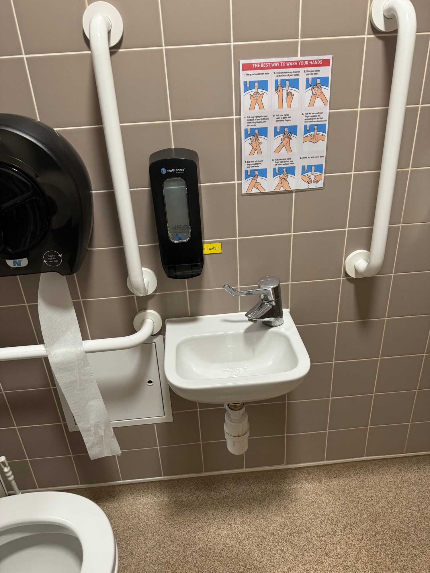 Lowered sink with a picture of how to wash your hands properly soap just to the left of the tap