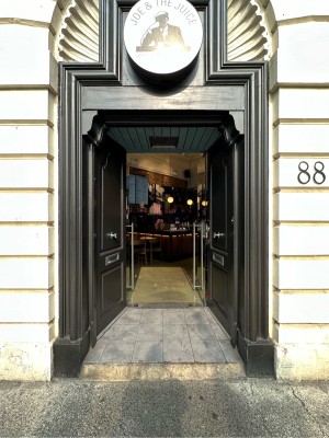 First set of black doors. Silver handles in centre of booths doors. Push to open.