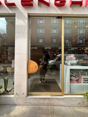 Glass door with gold frame. Wooden handle on left, push to open.