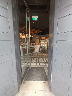 Glass door with silver vertical handle on right. Push to open.