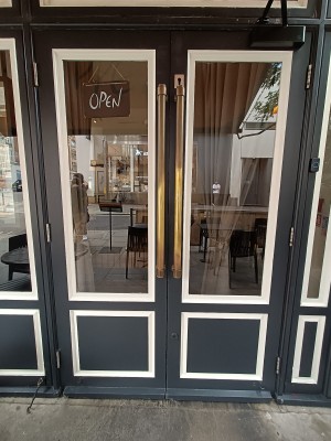 Glass doors with black frames. Golden handles in middle. Pull to open.