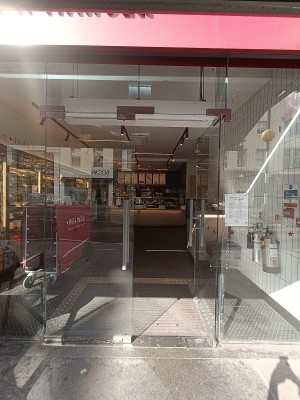 Glass doors with grey vertical handles in the middle. Push to open.