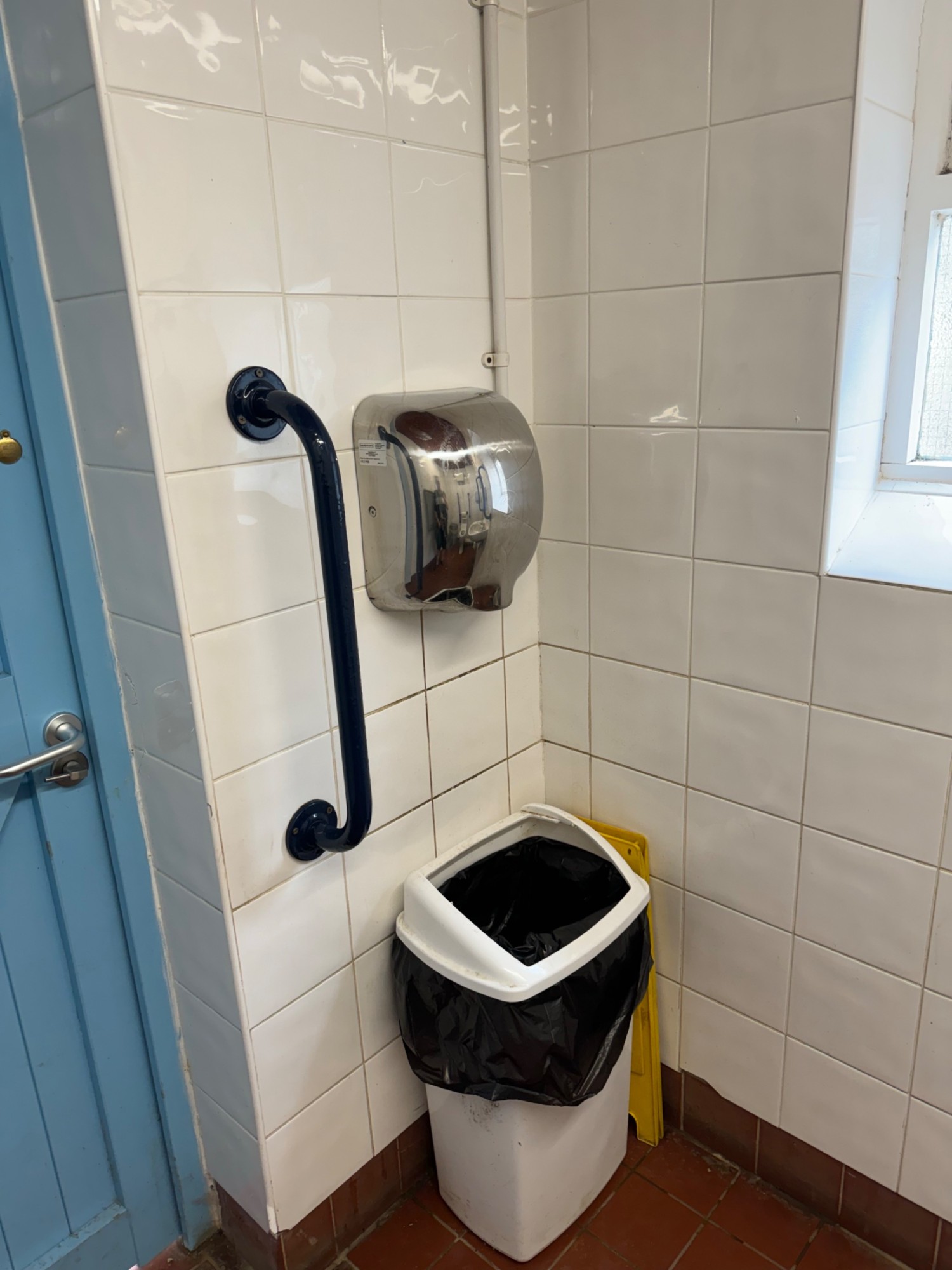 Hand dryer with grab rail on the left nex to the door and bin underneath