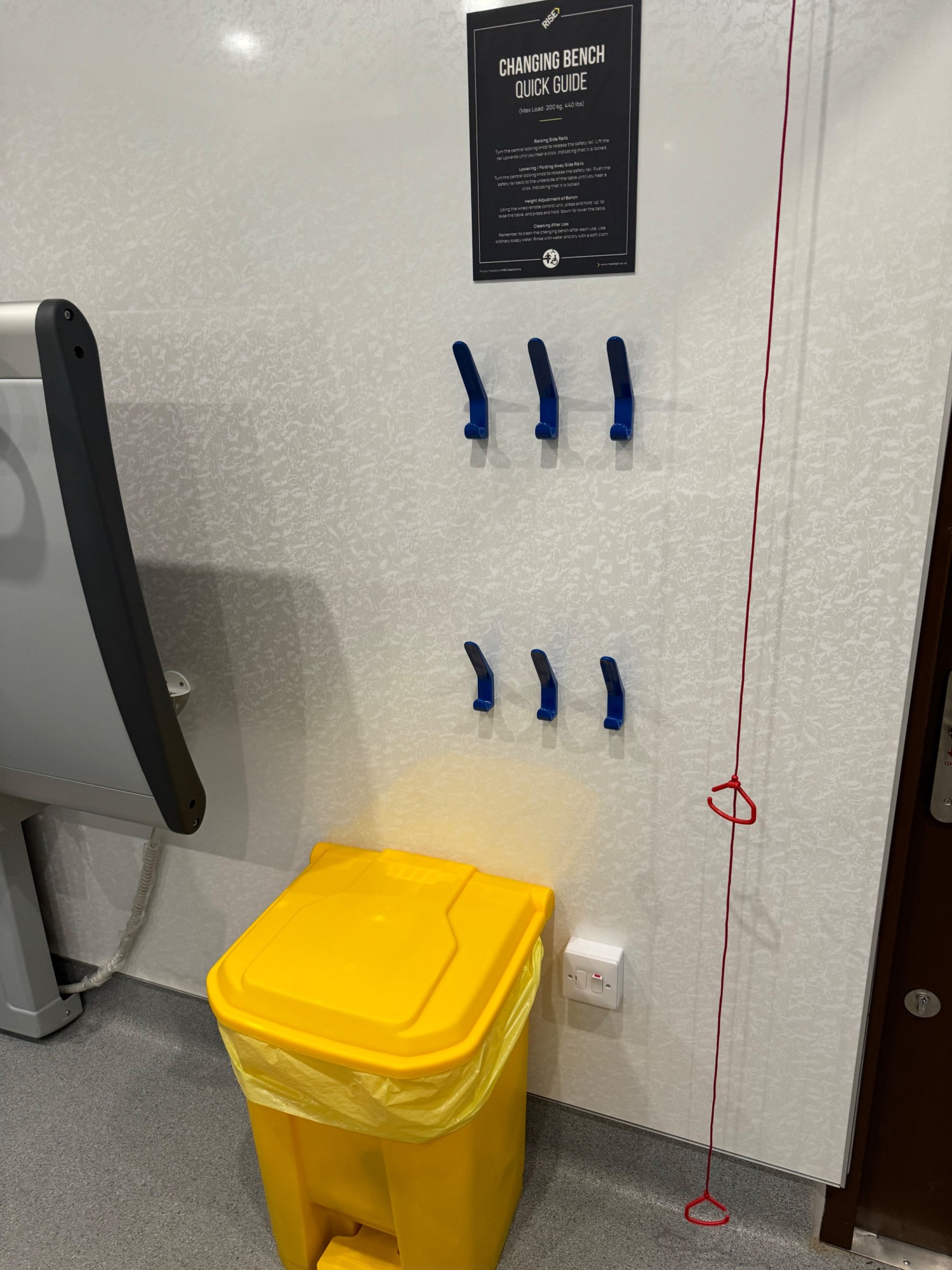 Hooks at seat height above sanity bin to the right of the door and pull cord to the right of the bin
