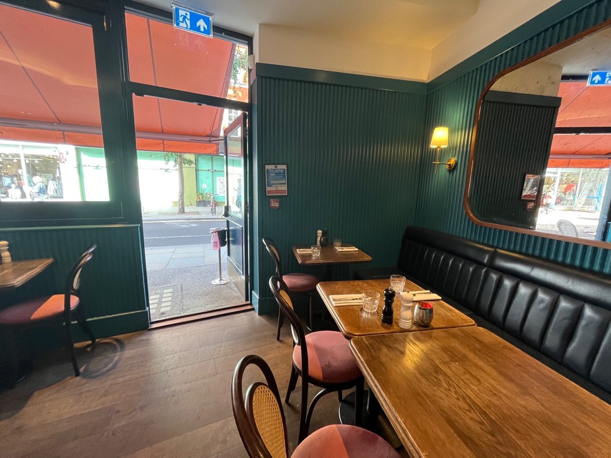 From end of bar facing left. Path straight. Tables and chairs left. Half booth right.