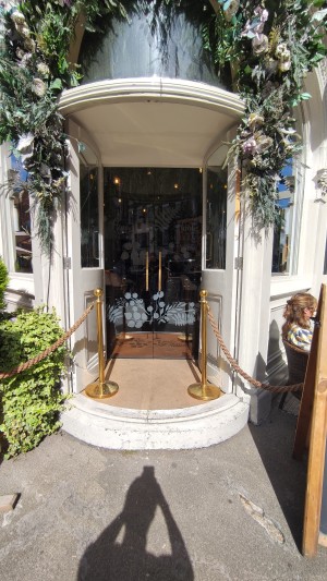 Facing from street facing the venue. Path ahead. One step up to white doors. Push in centre to open.