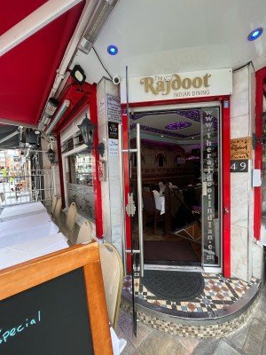 Single glass door in red metal frame. Pull silver metal handle from right to open. Sandwich board left.