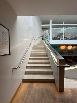 From 3rd floor landing, facing straight. First flight of stairs ahead. Silver handrails along left and right.