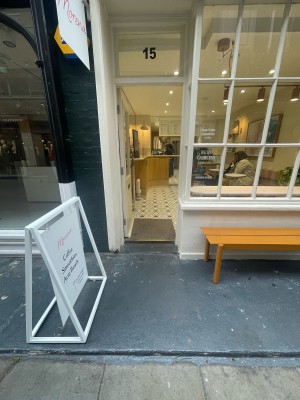 From pavement, facing straight. Path ahead leads to entrance. A-frame on left. Outdoor area on right.