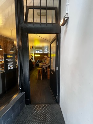 Facing entrance. Push gold metal handle on left to open.