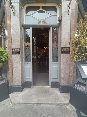 Glass door with grey frame. Gold pad on left. Push to open.