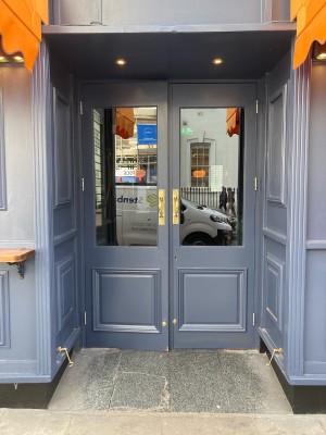 Double glass and blue wooden door. Pull open via handles in center.