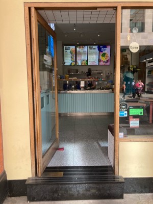 Glass door with wooden frame. Push open via handle on right.